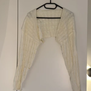 Vit stickad kofta från SHEIN - Säljer en vit, kort och stickad kofta från SHEIN i storlek M. Koftan har ett klassiskt kabelstickat mönster och långa ärmar. Perfekt att slänga över en topp för en mysig och stilren look.