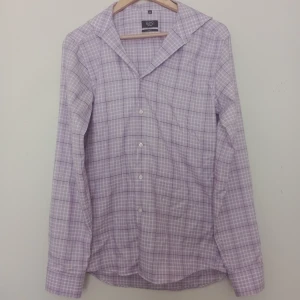 Ljuslila rutig skjorta Long Island - Snygg ljuslila rutig skjorta från Long Island. Skjortan har klassisk krage, knappar framtill och långa ärmar. Materialet är mjukt och lätt, perfekt för dig som gillar stilrena och fräscha plagg med lite färg.