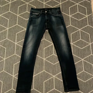 Replay Grover jeans mörkblå skinny - Snygga Replay Grover jeans i mörkblå tvätt med slitningar och skinny fit. Klassisk femficksmodell med detaljerade bakfickor och läderpatch i midjan. Jeansen har dragkedjegylf och är tillverkade i stretchig denim för en bekväm passform.