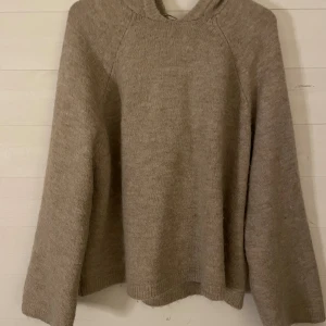 Beige stickad hoodie från Gina Tricot alpacka ull - Mysig beige stickad hoodie från Gina Tricot i storlek S. Tröjan har en avslappnad passform, lång ärm och stor huva. Perfekt för kyliga dagar och enkel att matcha med jeans eller leggings.