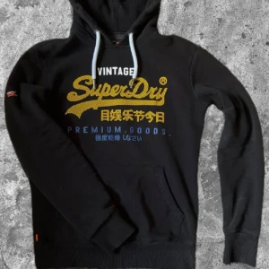 Svart Superdry hoodie - As fet hoodie från superdry i mycket bra skick! Xs men passar mer som S. Passar mig bra som är 180 men passar nån som är 175-183 typ. Passar till allt och är rätt varm perfekt till vintern😊 kom gärna med frågor 😝