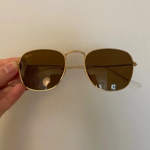 Ray-Ban solglasögon guld fyrkantig - Säljer ett par stilrena Ray-Ban solglasögon. Perfekt accessoar för soliga dagar! Ray-Ban Hexagonal RB3548N 001/57. Håller på att flytta så hittar ej fodralet skickar i ett chimi fodral istället för att de ej ska gå sönder.
