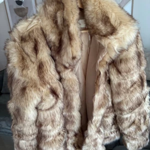 Beige pälsjacka med brun mönstring - Säljer en fluffig och mysig pälsjacka i beige med bruna inslag. Jackan har en klassisk krage och är helfodrad. Håller dig varm kyligare dagar. Nypris 800, aldrig använd endast testad.