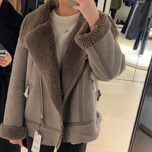 Beige teddyjacka med dragkedjor - Säljer en beige teddyjacka med bred krage och mysigt teddyfoder. Jackan har stora slag, synliga sömmar och dragkedjor på sidorna. Perfekt för dig som vill ha en chill och snygg look under kalla dagar. Nypris ca 1200kr 