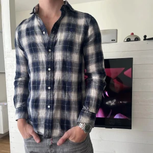 Rutig skjorta från Polo Ralph Lauren - Snygg rutig skjorta från Polo Ralph Lauren i klassisk passform. Skjortan är blå och vit med knappar framtill och broderad logga på bröstet. Perfekt för dig som gillar en avslappnad men stilren look. Skjortan sitter slim fit