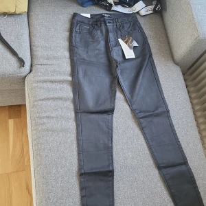 Svarta skinny jeans från My Tina's - Snygga svarta byxor från My Tina's i skinny fit med hög midja. Byxorna har klassisk femficksdesign och är tillverkade i ett stretchigt material som sitter tajt längs benen. Perfekta för dig som gillar en stilren och modern look.
