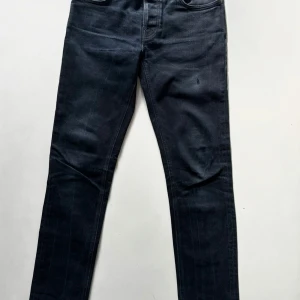 Mörkblå jeans från Nudie Jeans - Snygga mörkblå jeans från Nudie Jeans med klassisk femficksdesign och diskreta sömmar på bakfickorna. Jeansen har en smal passform och är tillverkade i mjukt denimtyg som sitter skönt hela dagen. Perfekta för dig som gillar stilrena och tidlösa jeans.