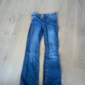 Blå bootcut jeans från Gina Tricot 158 - Snygga blå jeans från Gina Tricot i storlek 158. Modellen har klassisk femficksdesign, lätt utsvängda ben och normal passform. Jeansen är tillverkade i mjukt denimtyg och har en cool tvättad look med ljusare partier.