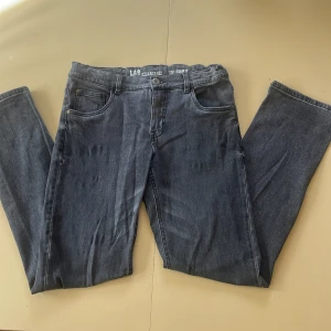 Grå jeans från LAB Industries - Snygga grå jeans från LAB Industries med regular fit och klassisk femficksdesign. Jeansen har en retro vibe och raka ben, perfekt för dig som gillar enkel och stilren look. Materialet är slitstarkt denim och midjan är normal. Passar dig som vill ha bekväma och tidlösa jeans.