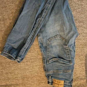 Blå jeans Molly från Perfect Jeans XS - Säljer ett par blå jeans från Perfect Jeans, modell Molly i storlek XS. Byxorna har en klassisk femficksdesign med en extra stor ficka på ena benet och snygga sömmdetaljer. Jeansen är i mjuk bomullsdenim och har knappstängning framtill.