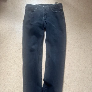 Emporio Armani J45 Regular Fit Jeans - Mörkblå jeans från Emporio Armani, modell J45 Regular Fit. Klassisk femficksdesign med kontrastsömmar och metallogo på bakfickan. Raka ben och normal passform, tillverkade i mjukt bomullsjeansmaterial. det är storlek 30 