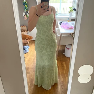 Ljusgrön långklänning från NA-KD - Supersnygg ljusgrön långklänning från NA-KD med tunna axelband och ett unikt strukturerat mönster. Klänningen har en smickrande passform, knytning i ryggen och är perfekt för sommarens alla tillfällen. Materialet känns lätt och luftigt. Använd en gång💗