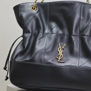 Svart axelväska från Saint Laurent - Säljer en svart axelväska från Saint Laurent i mjukt skinn med quiltad design och guldfärgade kedjedetaljer. Väskan har YSL-logga framtill och dragsko i sidorna. Perfekt för dig som vill ha en lyxig och stilren väska med plats för allt du behöver.