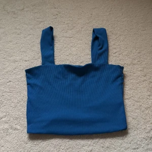 Blå ribbad linnetopp från Amisu - Säljer en blå ribbad linnetopp från Amisu i storlek XS. Toppen har breda axelband och är croppad i modellen, perfekt att styla med höga jeans eller kjol. Enkel och stilren design med en snygg struktur i tyget.