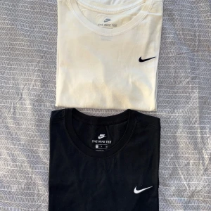 Nike Tee svart & vit t-shirt - Två klassiska Nike Tee t-shirts, en i svart och en i vit. Båda har korta ärmar, rund hals och den ikoniska Nike Swoosh-loggan broderad på bröstet. Tillverkade i mjuk bomull som är skön mot huden. Perfekt för dig som gillar enkel och sportig stil. En är i storlek S och den andra storlek M, men skulle säga att båda sitter som en storlek M.