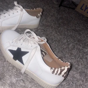 Vita sneakers med zebradetalj och stjärna - Snygga vita sneakers med svart stjärna på sidan och zebramönstrad detalj vid hälen. Köpte dessa skor här på plick men säljer då de va för små för mig. 