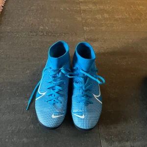 Blå Nike mercurial inomhus fotbollsskor med snörning - Säljer ett par blå Nike mercurial superfly inomhus fotbollsskor med vita detaljer och snörning. 