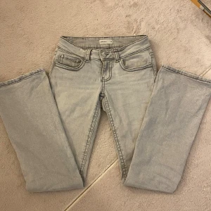 Bootcut jeans - Snygga ljusgrå jeans med bootcut passform. Jeansen har låg midja och markerade sömmar som ger en trendig look. Perfekta för dig som vill ha en stilren men edgy vibe.
