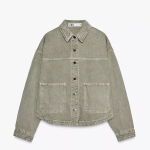 Beige overshirt från Zara i jeans -  Grön jacka från Zara i jeansmaterial. Jackan har raka linjer, två stora fickor framtill och knäppning med metallknappar. Perfekt för lager-på-lager och ger en avslappnad vibe till din outfit.