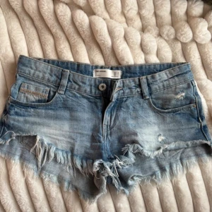 Blå jeansshorts med fransar från Zara - Supersnygga shorts som är lågmidjade. Använd max 5 gånger så bra skick! Köpta gör 300kr och säljs inte längre