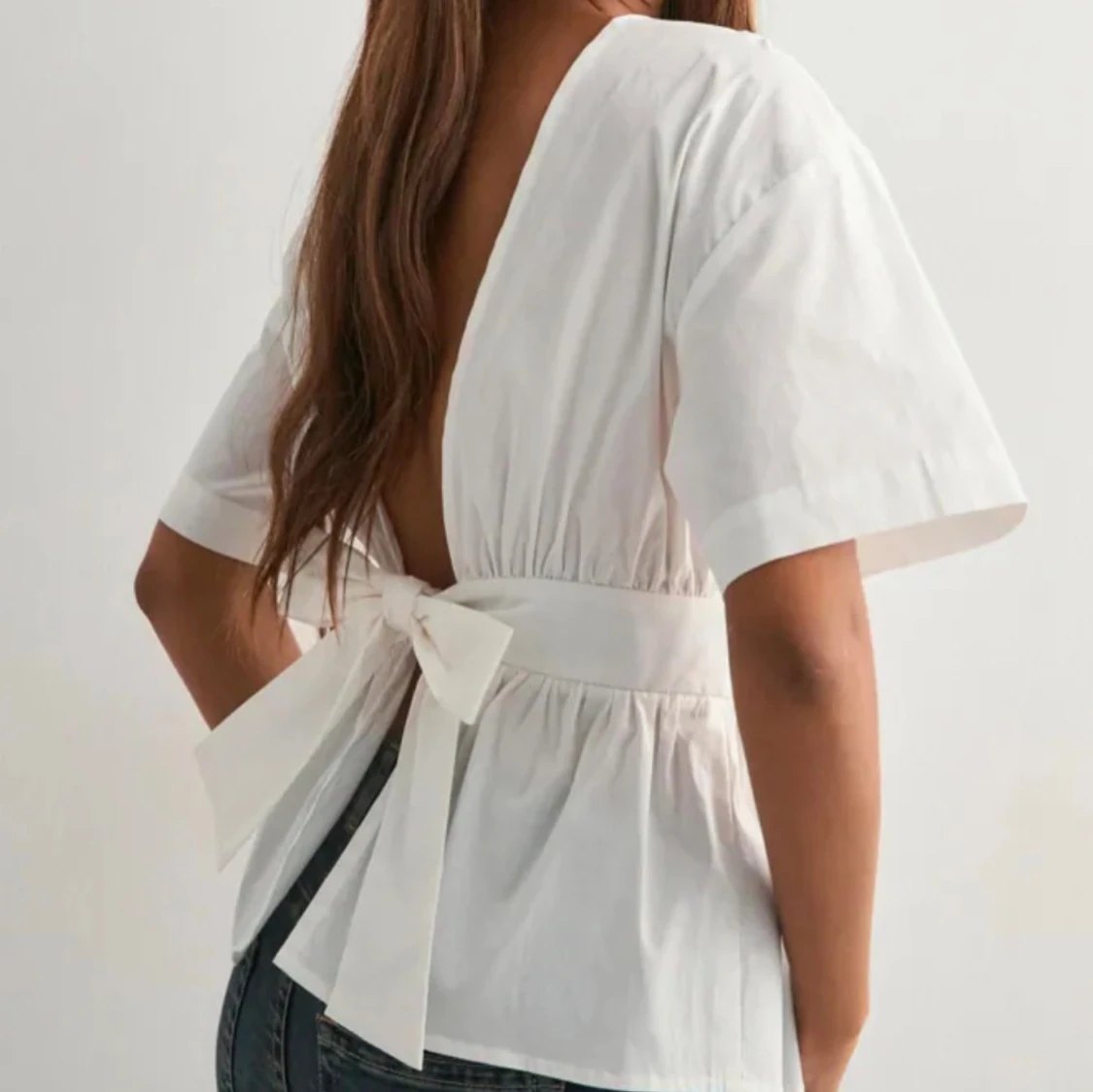 Vit blus med öppen rygg och rosett