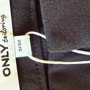 Svarta kostymbyxor från ONLY - Svarta kostymbyxor från ONLY tailoring i klassisk rak modell. Byxorna har en stilren look och är tillverkade i ett mjukt material som ger en dressad känsla. Perfekta för dig som gillar en clean och enkel stil.