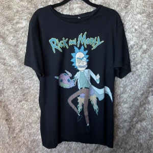 Rick and Morty svart t-shirt XL - Svart t-shirt med stort Rick and Morty-tryck framtill. Klassisk rund hals och korta ärmar. Tillverkad i mjuk bomull, perfekt för dig som älskar serien och vill sticka ut med en cool och bekväm tee.