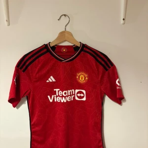 Manchester United Garnacho tröja Adidas - Manchester United matchtröja med Garnacho 17 på ryggen. Röd med svarta detaljer och vita tryck, officiell Premier League badge på ärmen. Använd några gånger. Använd väl och tagen hand om.