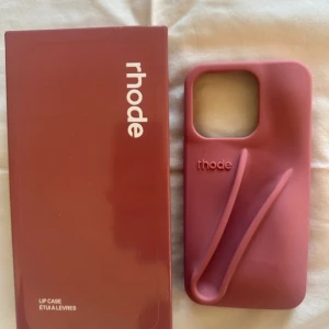 Rhode Lip Case Salty Tan – iPhone 13/14/15 Pro - Rhode’s Lip Case i nyansen Salty Tan – en varm beige/sand-ton som är lätt att matcha. ✔ Passar iPhone 13 Pro, 14 Pro & 15 Pro ✔ Plats för din favorit Rhode Peptide Lip Tint (läppglans ingår ej, endast med på bild för att visa funktion)❗️ ✔ Färgen “Salty Tan” – trendig, tidlös och lätt att matcha 💌 Skickas snabbt & säkert! 📦 Ny i förpackning. #RhodeLipCase #RhodeSkin #HaileyBieber #LipCase #RhodeCase #SaltyTan #iPhoneCase