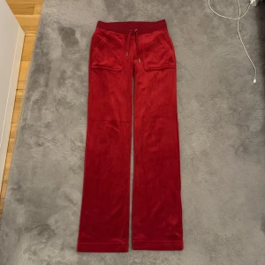 Röda velourbyxor Juicy Couture XXS - Röda mjukisbyxor från Juicy Couture i velour med fickor bak. Endast använt ett par gånger och ser nya ut, inga fläckar eller skavanker. Skriv gärna för fler bilder, frågor eller prisförslag.