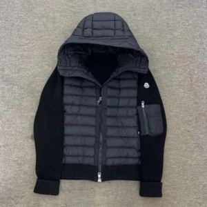 Svart Moncler pufferjacka med huva - Snygg svart pufferjacka från Moncler med stickade ärmar och vadderad kropp. Jackan har huva, dragkedja framtill och en extra ficka med dragkedja på ärmen. Perfekt för dig som vill ha en stilren och sportig look med exklusiv känsla.