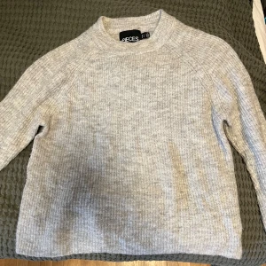 Ljusgrå stickad tröja från Pieces - Mysig ljusgrå stickad tröja från Pieces med rund halsringning och lång ärm. Tröjan har en enkel, ribbad struktur och är perfekt för kyliga dagar. Snygg och enkel att matcha med jeans eller kjol. Säljer bara tröjan eftersom den är för liten för mig. Knappt använt den alls. Original pris: 500kr Pris kan diskuteras