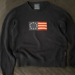 Mörkblå stickad tröja Sebago  - Mörkblå stickad tröja från Sebago i storlek XL men passar mer som L. Ribbstickade muddar vid ärmslut och nederkant ger en snygg och klassisk look. Perfekt för dig som gillar preppy stil.