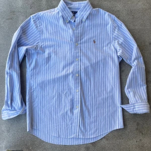 Blåvit randig skjorta från Ralph Lauren - Somrig skjorta från Ralph Lauren i riktigt bra skick. Pass formen är classic. Vid minsta lilla fundering är det bara att fråga.