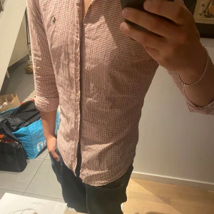 Rutig skjorta från Polo Ralph Lauren - Säljer en klassisk rutig skjorta från Polo Ralph Lauren i storlek S. Skjortan är vit med röda och brun/gröna rutor, har knappar framtill och lång ärm. Väldigt skön och stilren. I princip i ny skick.