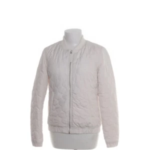 Vit quiltad bomberjacka - Snygg vit quiltad bomberjacka med dragkedja framtill och ribbade muddar. Jackan har en stilren look och passar perfekt till lager-på-lager-stil. Lätt vadderad och med klassisk bomberkrage.