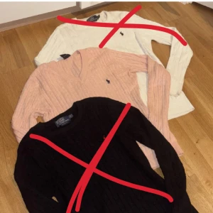  Polo Ralph Lauren - Kabelstickad tröja från Polo Ralph Lauren i klassisk modell. Finns endast en kvar: ljusrosa med marinblå logga. Tröjan har en v-ringad hals och långa ärmar. Perfekt för en stilren och preppy look. 