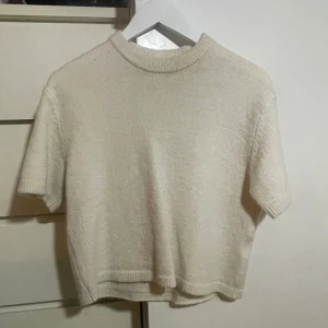 Beige stickad kortärmad tröja - Supermjuk och enkel beige stickad tröja med korta ärmar och ribbade kanter vid hals, ärmslut och nederkant. Perfekt för lager-på-lager och chill. Säljer då den inte används längre. Pris kan diskuteras💞