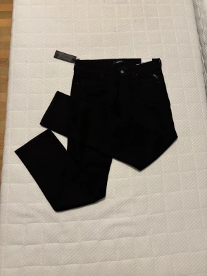 Svarta Replay straight jeans - Säljer ett par svarta Replay jeans i straight fit. Klassisk femficksmodell med snygga detaljer och logga på fickan. Jeansen har normal midja och raka ben, perfekta till sneakers eller boots. Materialet är mjukt och följsamt för en skön känsla hela dagen.