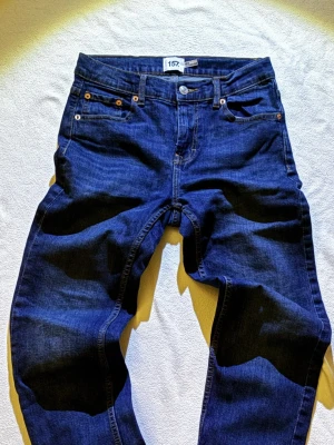 Blå jeans från 157, storlek 160 - Säljer ett par klassiska blå jeans från 157 i storlek 160. Jeansen har fem fickor, dragkedja och knapp framtill samt snygga kontrastsömmar. Materialet är slitstarkt denim i bomull och passformen är normal med raka ben.