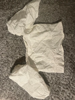 Vit broderad blus med puffärm - Säljer en superfin vit blus med broderade detaljer och hålmönster. Toppen har puffiga långärmar och dragkedja i sidan för enkel påklädning. Perfekt till sommaren för en fräsch look.