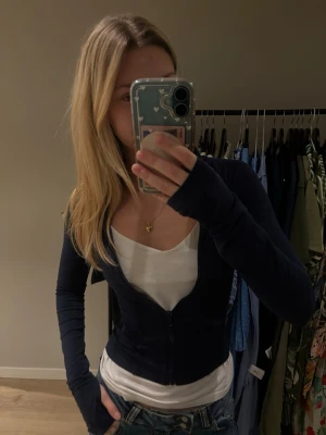 Mörkblå zip-kofta från Gina Tricot - Säljer en mörkblå, tight kofta från Gina Tricot i storlek S. Koftan har dragkedja framtill, lång ärm och är gjord i mjukt bomullsmaterial. Perfekt att slänga över ett linne eller t-shirt för en chill look. Funkar även till träning! 