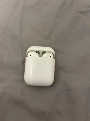 Apple AirPods (2nd generation) - Säljer ett par Apple AirPods (2nd gen) med laddningsetui. Fungerar utmärkt, med normalt bruksslitage på etuiet. Perfekt för trådlös musik och samtal, kompatibla med iPhone och andra enheter via Bluetooth.