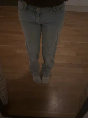 Ljusblå raka jeans - Säljer ett par gamla ljusblå jeans med klassisk femficksdesign och raka ben. Jeansen har normal passform och midja, och är tillverkade i jeansmaterial. Perfekta för en chill och avslappnad stil. 