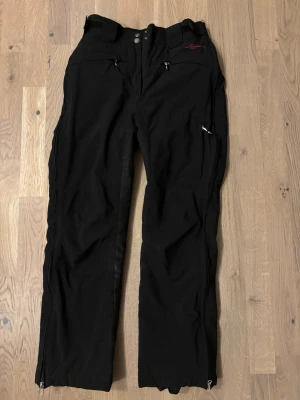 Svarta termos ridbyxor från Cavallo - Säljer ett par svarta ridbyxor från Cavallo med helskoning i mocka. Byxorna har dragkedjor vid fickorna och bensluten, samt justerbar midja med kardborre. Perfekta för dig som vill ha funktionella och snygga ridbyxor.