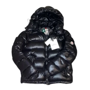  Moncler Maya - Säljer en svart pufferjacka från Moncler med huva och dragkedja framtill. Jackan har Moncler-logga på ärmen och klassisk quiltad design. Perfekt för kyliga dagar och riktigt snygg streetstil. Skicket är 10/10, säljer för 7999. Har även nfc skan. 