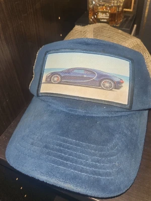 En blå mocka kepsen från perik. - Säljer du denna keps från perik [limiterade edition] tror de bara släpptes runt 50st, Snygg truckerkeps i blå mockaliknande finish framtill med beige mesh baktill. På framsidan sitter ett broderat/tryckt tygmärke med motiv av en sportbil, vilket ger kepsen en exklusiv och sportig look. Justerbar snapback baktill för bra passform. Märke: [perik] mer bilder och pris kan diskuteras. Kepsen i sig är inte så värst förstöra förutom att den är lite backat luttrad och lite smutsig. [Pris erbjudning]