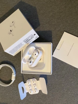 AirPods Pro 2 - Apple AirPods Pro i mycket fint skick, komplett med originalförpackning, laddningskabel, extra öronproppar och manualer. Trådlösa hörlurar med aktiv brusreducering och laddningsetui. Både hörlurar och etui har god batterinivå. Inga synliga defekter eller slitage.