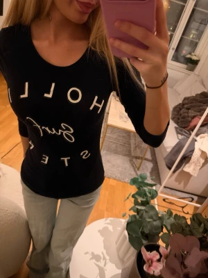 Svart trekvarts armad topp från Hollister - Säljer en svart långärmad topp från Hollister med vit text 'Hollister Surf' framtill. Storlek Xs 💖