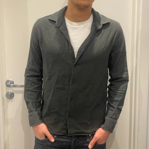 Mörkgrön skjorta från Zara - Säljer en stilren mörkgrön skjorta från Zara i mjuk bomull. (Färgen syns inte så bra i bilden). Skjortan har klassisk krage, knäppning framtill och långa ärmar med manschetter. Perfekt till jeans eller chinos för en clean look.